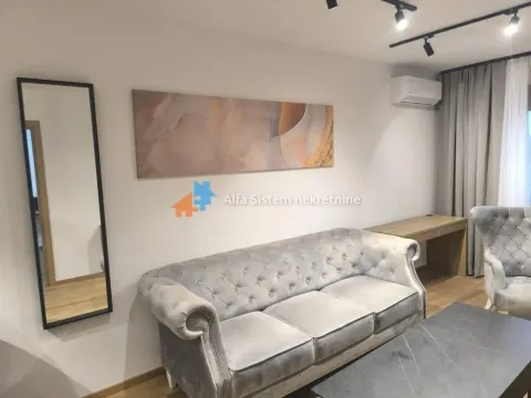Living room with a grey sofa, armchair, wall mirror, and artwork. - image 9
