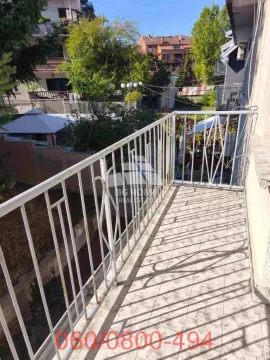 Pogled sa popločanog balkona sa belom ogradom na okolne zgrade i zelenilo. - image 17