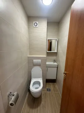 Small bathroom with a toilet, washbasin, and floor drain. - image 8
