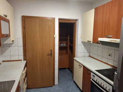 Kuhinja sa drvenim kuhinjskim elementima i ostavom u pozadini. - image 3