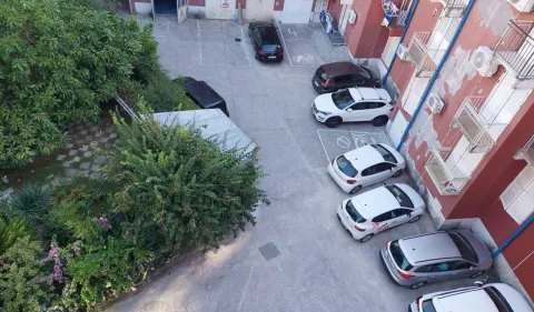 Pogled odozgo na dvorište zgrade sa parkingom i zelenilom. - image 5