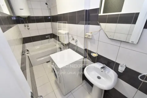 Small bathroom with a bathtub, washbasin, and washing machine. - image 9