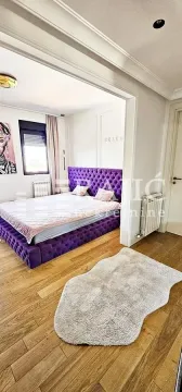 Furnished bedroom with a large purple bed and hardwood flooring. - image 9