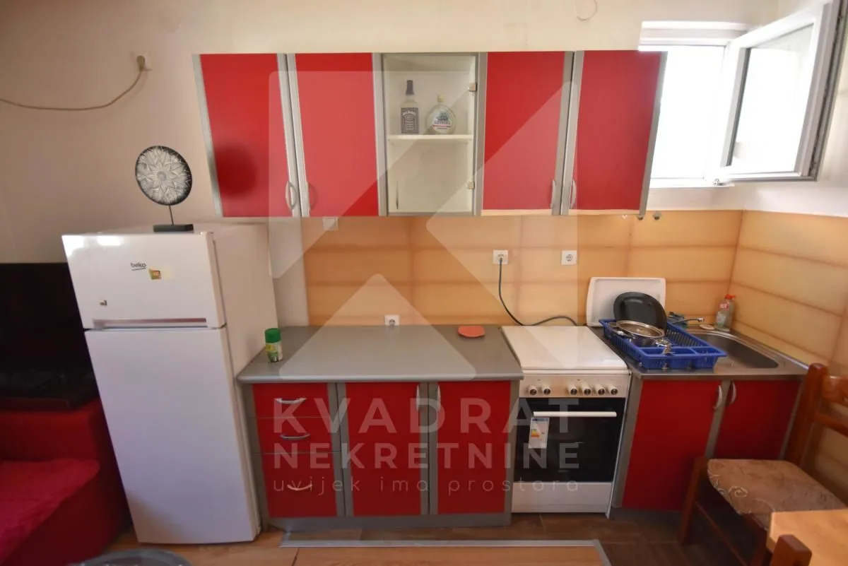 Smaller kitchen with red cabinets and a refrigerator.