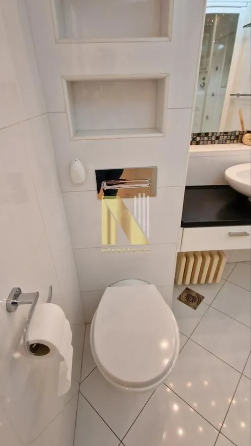 Pogled na kupatilo sa WC šoljom, ugradnim nišama i umivaonikom.