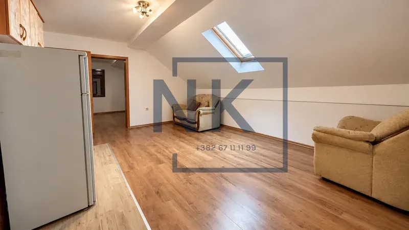 Attic space with wooden flooring, a skylight, and upholstered furniture.