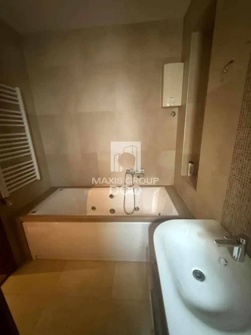 Bathroom equipped with a bathtub, washbasin, and neutral-toned tiles.