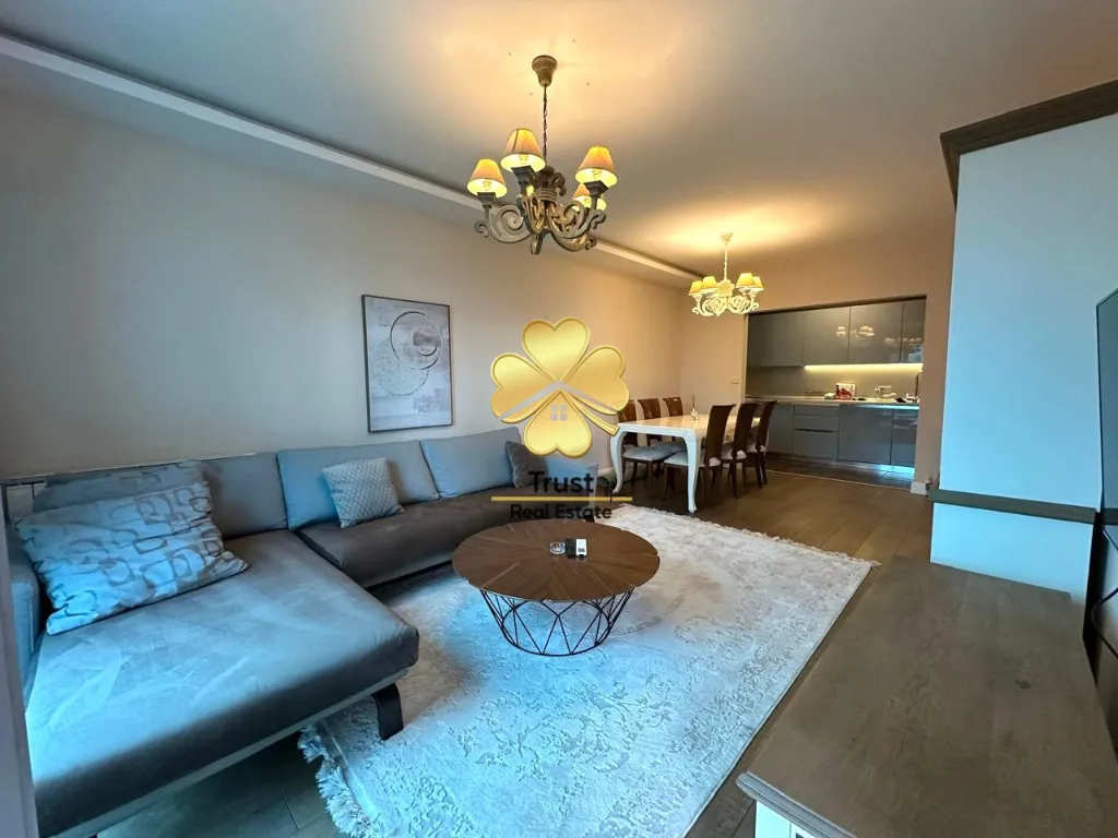 Spacious living room with a sofa and a dining area in the background.