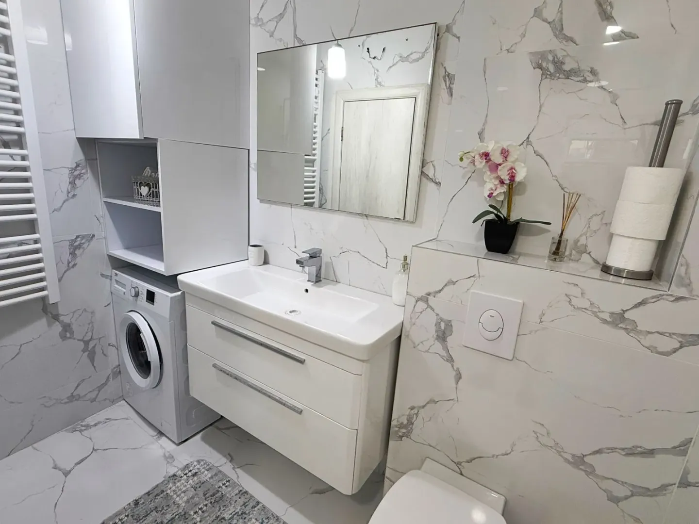 Modern bathroom equipped with a washbasin, mirror, and washing machine.