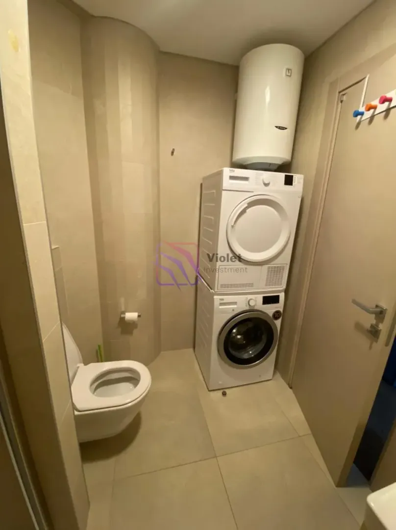 Bathroom equipped with a toilet, washing machine, dryer, and water heater.