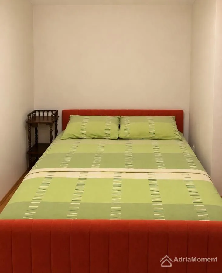 Spavaća soba sa krevetom i noćnim stočićem između zidova.