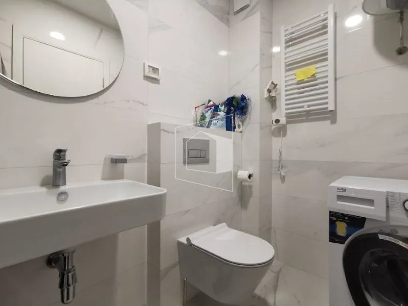 Moderno opremljeno kupatilo sa umivaonikom, šoljom i veš mašinom.