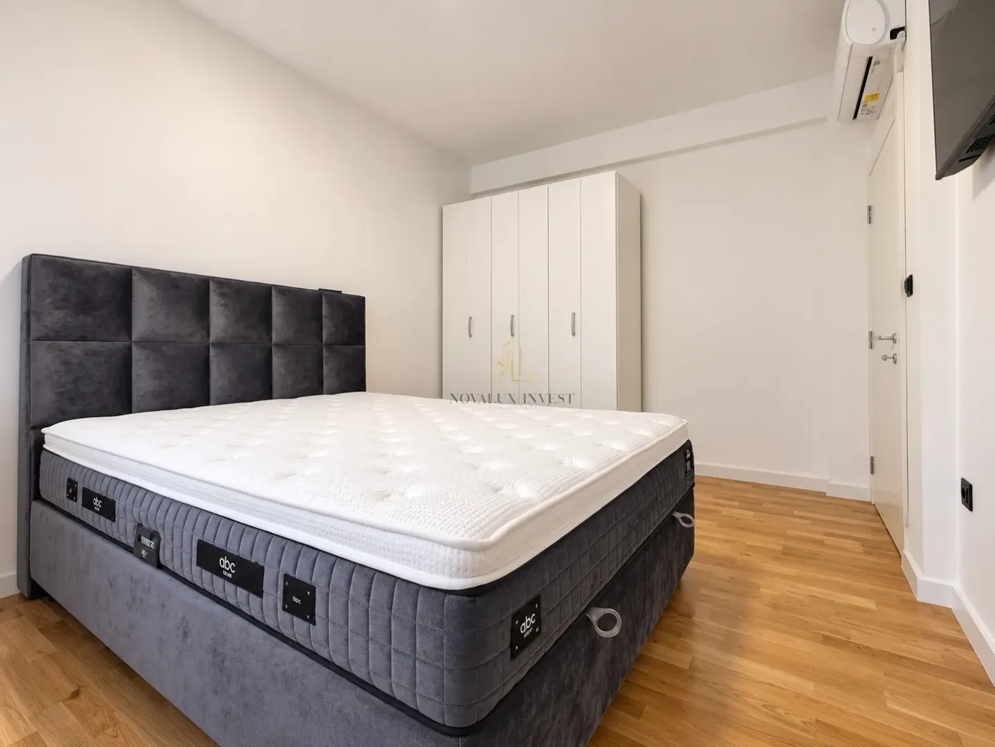 Bedroom featuring a double bed, a white wardrobe, and wooden flooring.