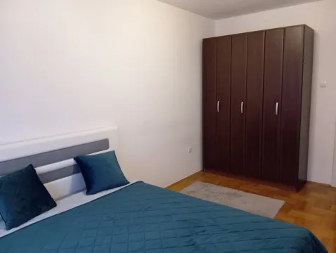 Svijetla spavaća soba sa bračnim krevetom i drvenim ormarom. - image 6