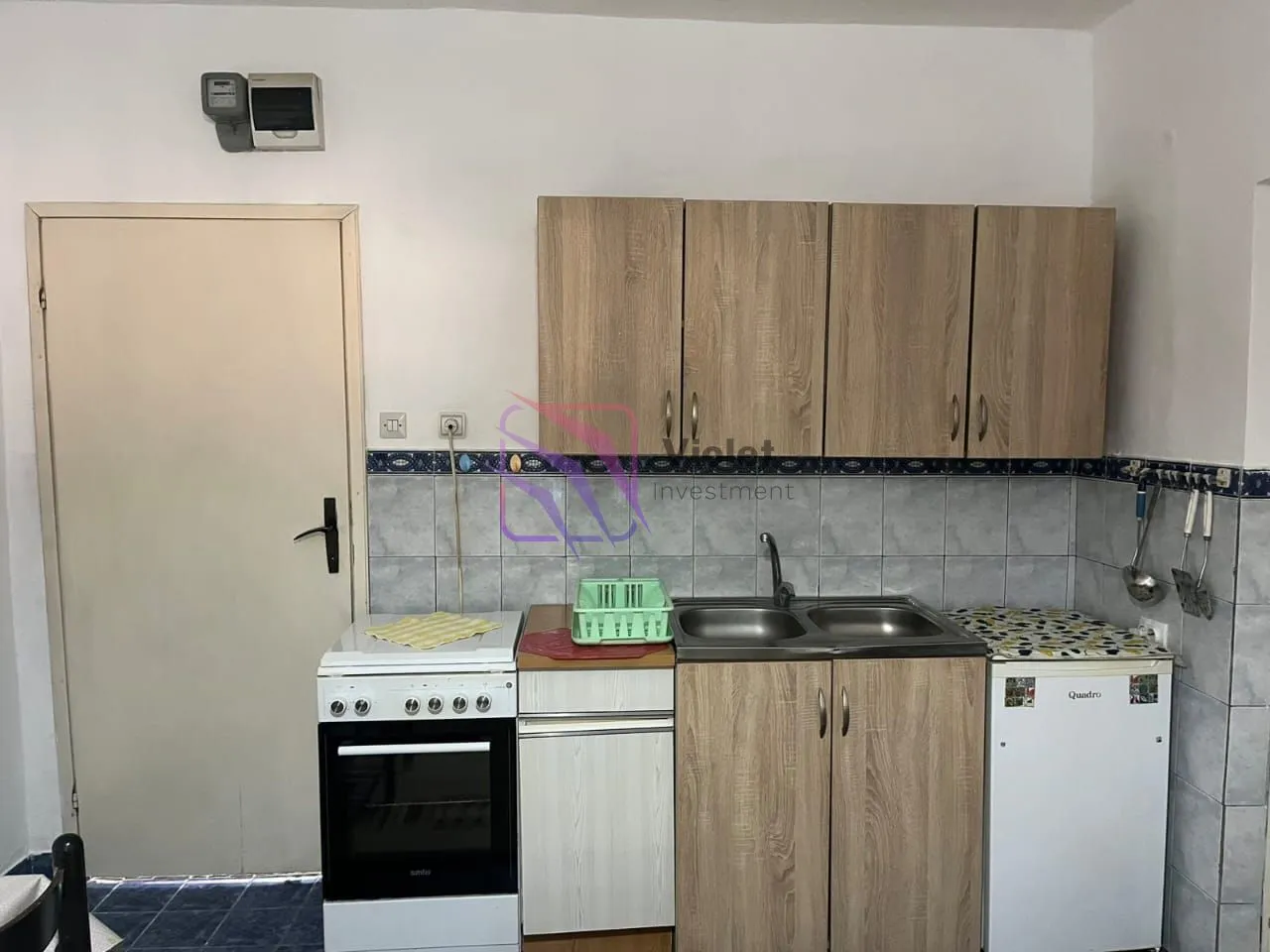 Small kitchen with wooden cabinets, stove, and sink.