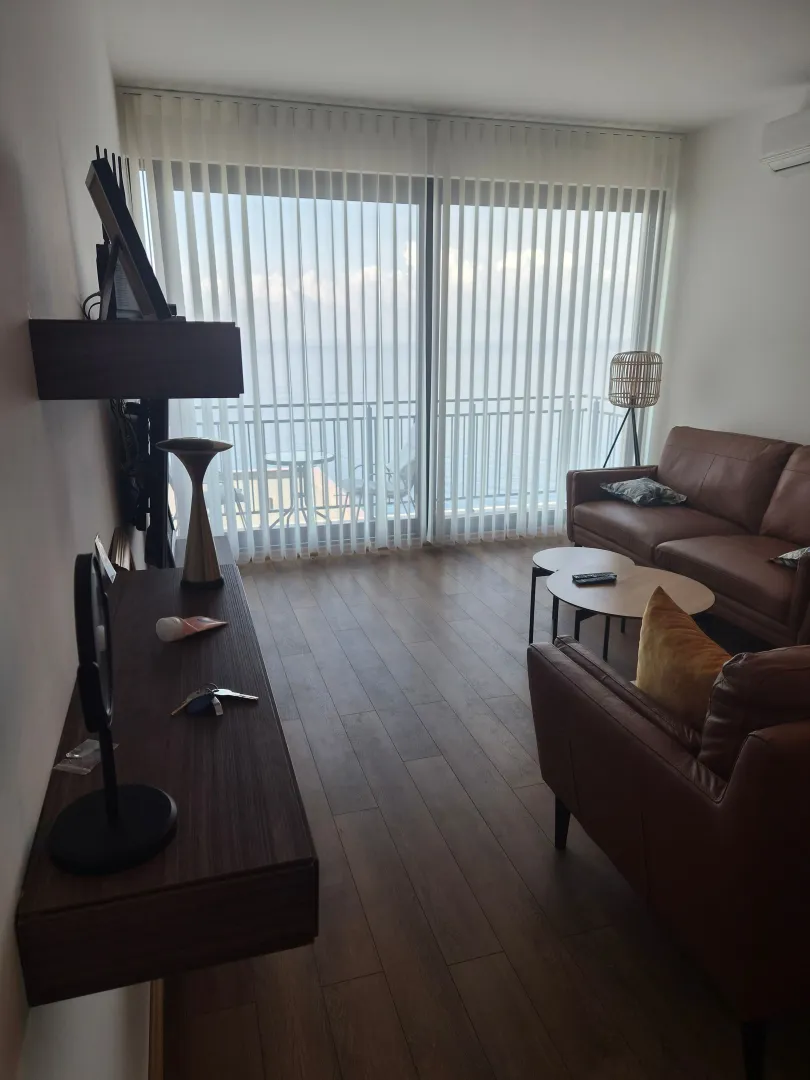 Bright living room with sofa set and a view of the terrace and sea.