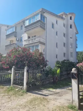 Pogled na spoljašnjost stambene zgrade sa uređenim dvorištem i ogradom. - image 2
