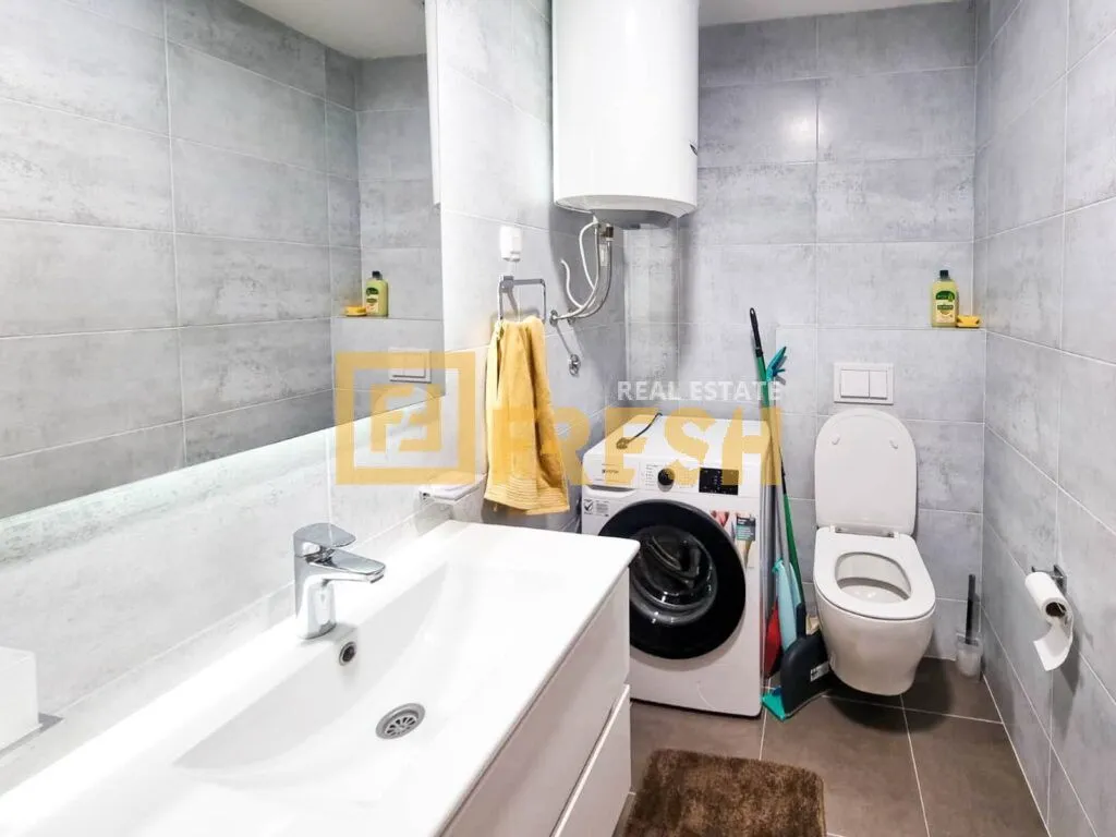 Moderne kupatilo sa umivaonikom, veš mašinom i WC šoljom.
