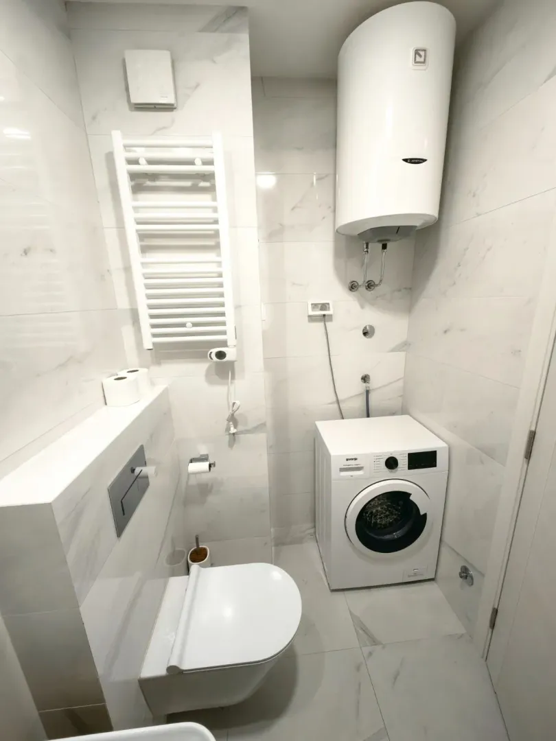 Moderne kupatilo sa wc šoljom, veš mašinom i bojlerom.