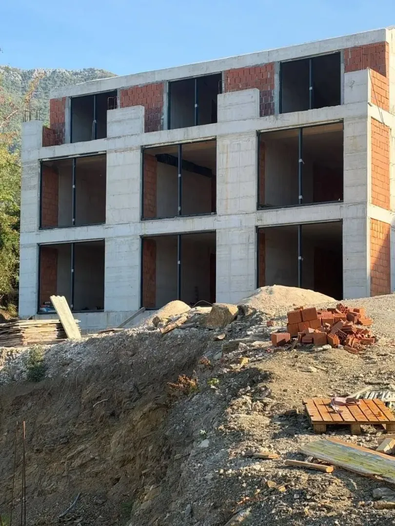 Pogled na spoljašnjost stambene zgrade u izgradnji sa betonskom konstrukcijom i ciglom.