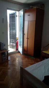 Spavaća soba sa drvenim ormarom, krevetom i izlazom na terasu. - image 8
