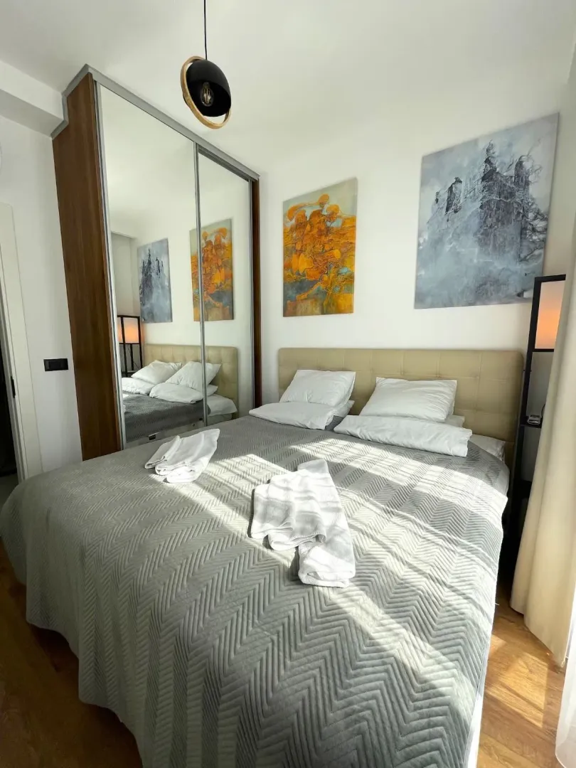 Bedroom with a double bed, a large mirrored wardrobe, and wall art.