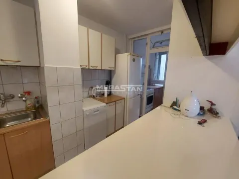 Kuhinja sa drvenim elementima, frižiderom i šankom. - image 9