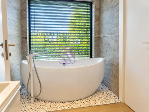 Modern bathroom with a freestanding bathtub and decorative pebbles. - image 23