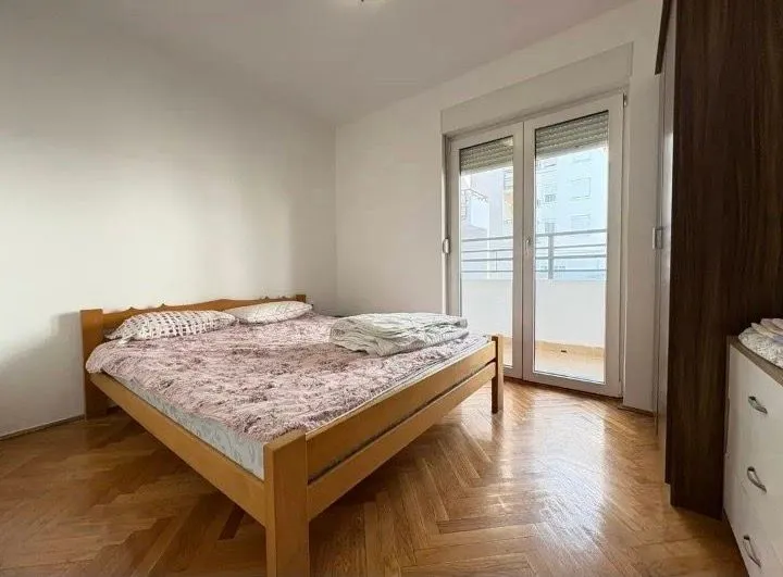 Bedroom with a double bed, parquet flooring, and balcony access.