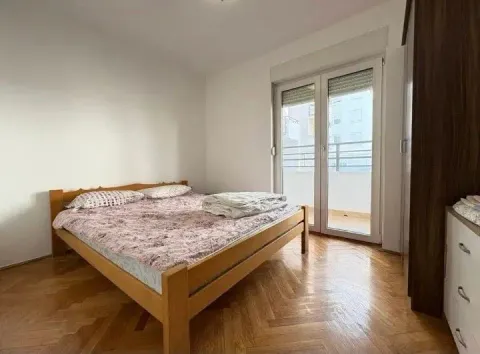 Bedroom with a double bed, parquet flooring, and balcony access. - image 4