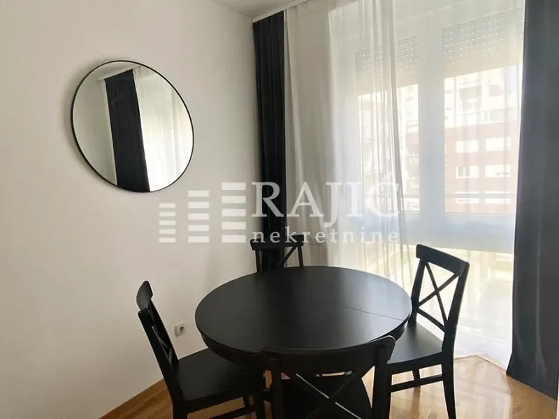 Dining area with a black table and chairs near the window.