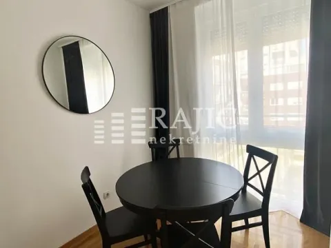 Dining area with a black table and chairs near the window. - image 4