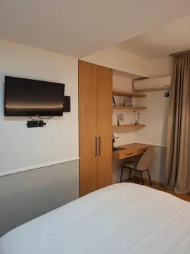 Furnished bedroom with a bed, desk, and wardrobe. - image 10