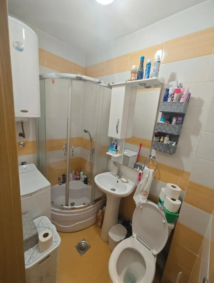 Manje kupatilo sa tuš kabinom, umivaonikom i veš mašinom.