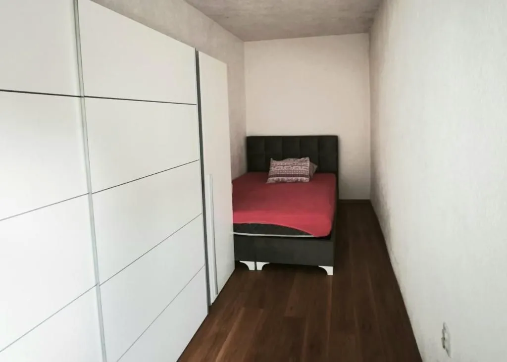 Small bedroom with a bed and a large fitted wardrobe.