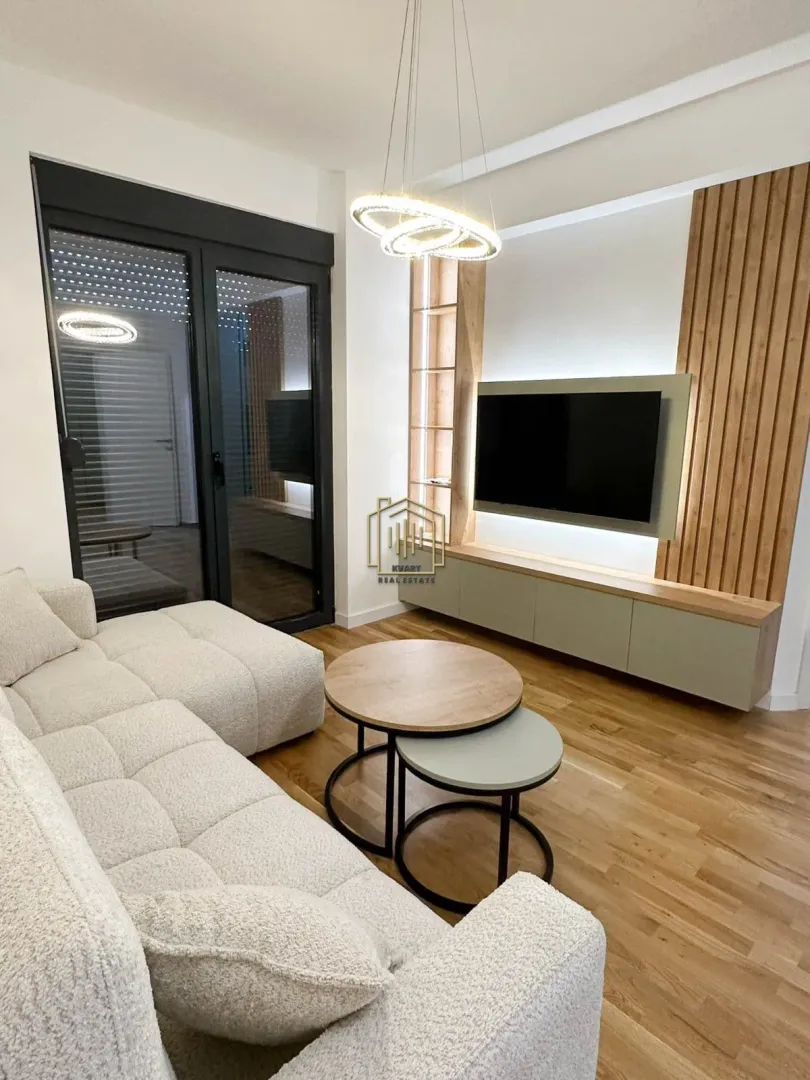 Moderan dnevni boravak sa garniturom, TV-om i izlazom na terasu.