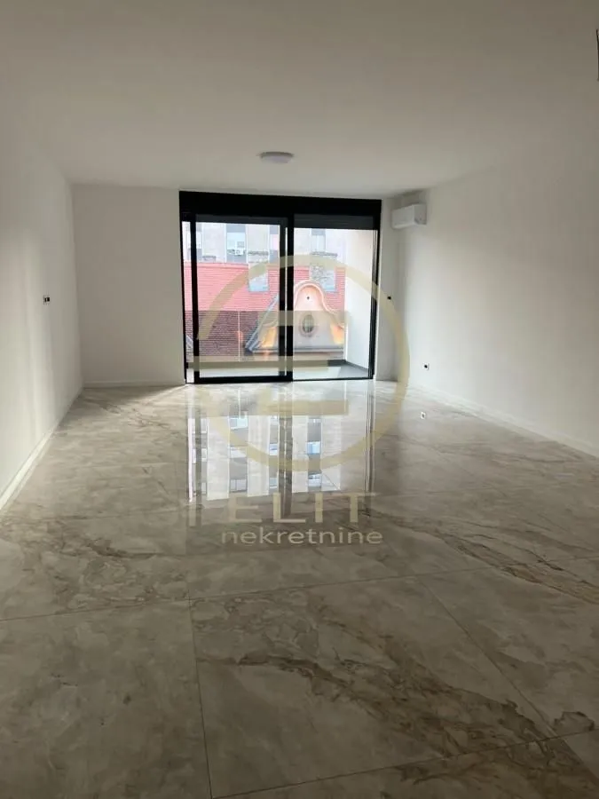 Empty room with glossy ceramic floor tiles and an exit to the terrace.