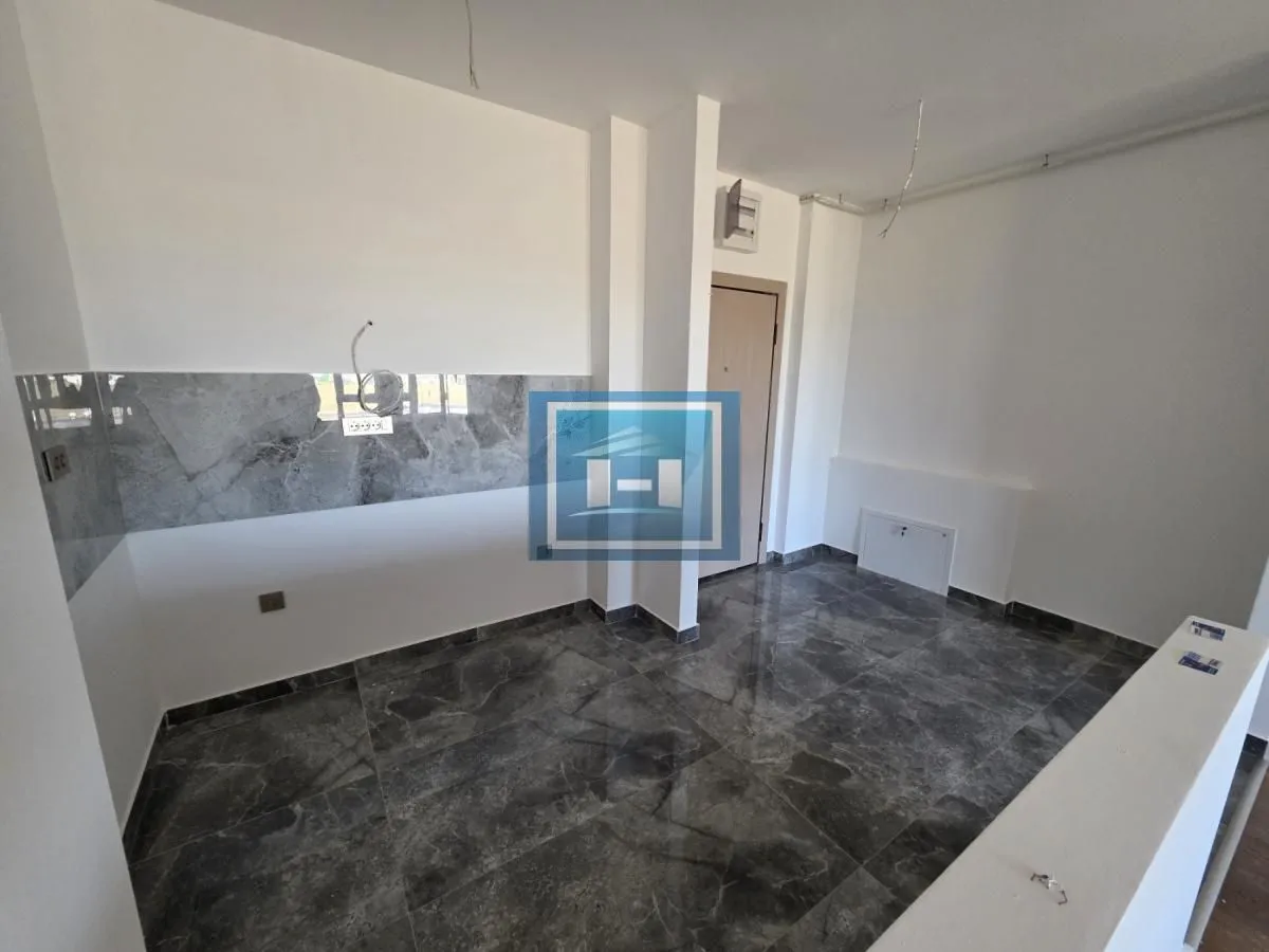 Nenameštena kuhinja sa sivim pločicama i pripremljenim instalacijama.