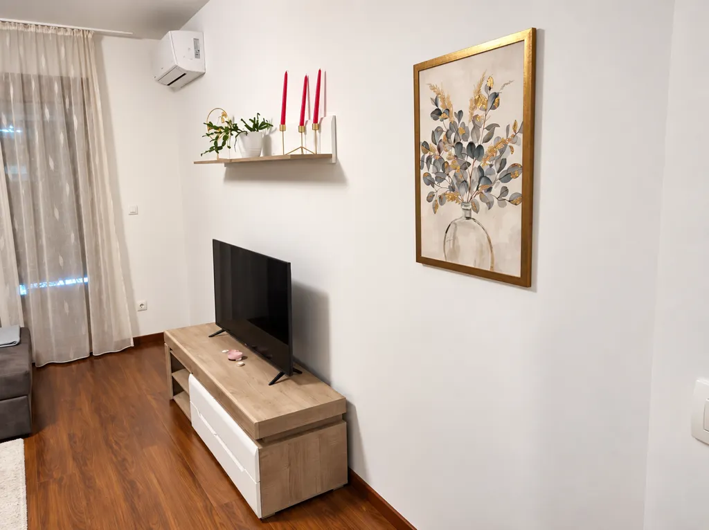 Dnevni boravak sa TV komodom i slikom na zidu.