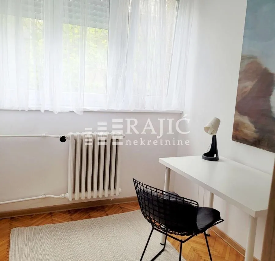 Small room with a desk and a window covered with curtains.