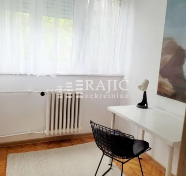 Small room with a desk and a window covered with curtains. - image 6