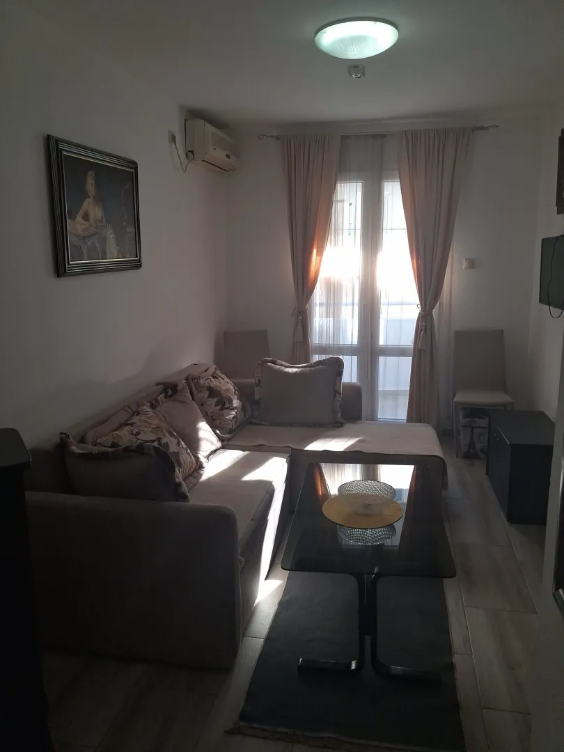 Living room with a sectional sofa, coffee table, and a window with curtains.