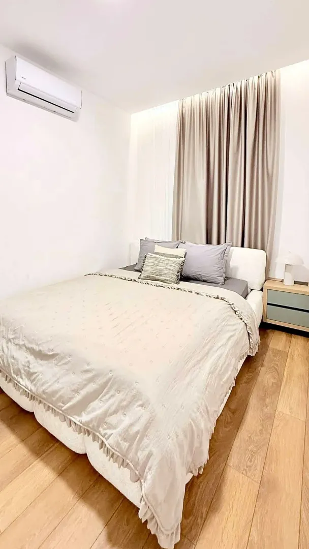 Cozy bedroom with a double bed, wooden flooring, and an air conditioning unit.