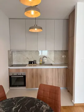 Moderna kuhinja sa ugrađenim elementima i trpezarijskim stolom u prvom planu. - image 10
