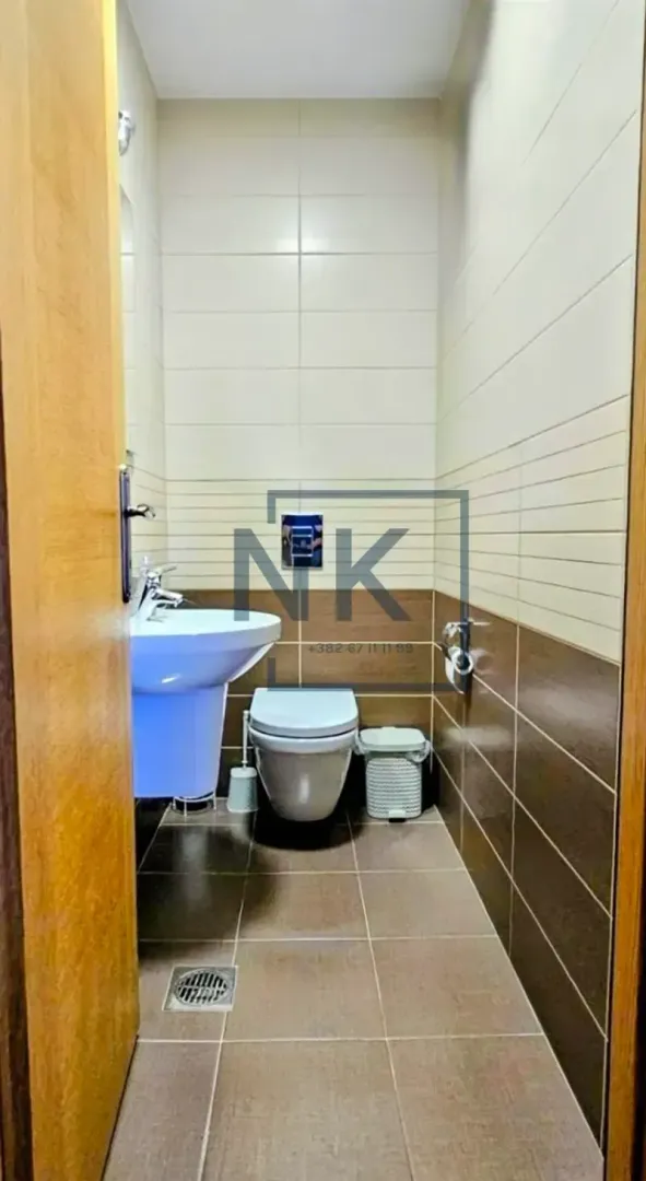 Small bathroom with a sink and toilet, tiled with ceramic tiles.