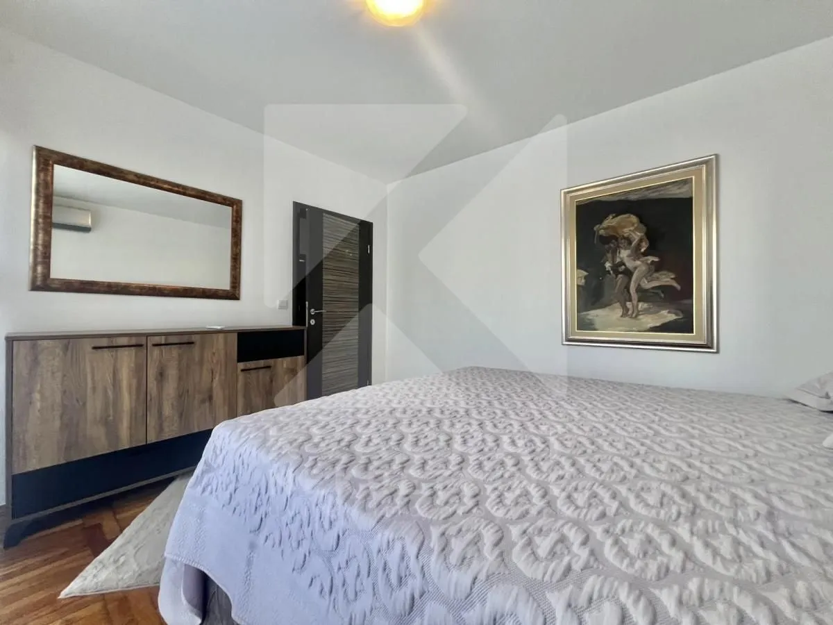 Furnished bedroom with a double bed, chest of drawers, mirror, and artwork on the wall.