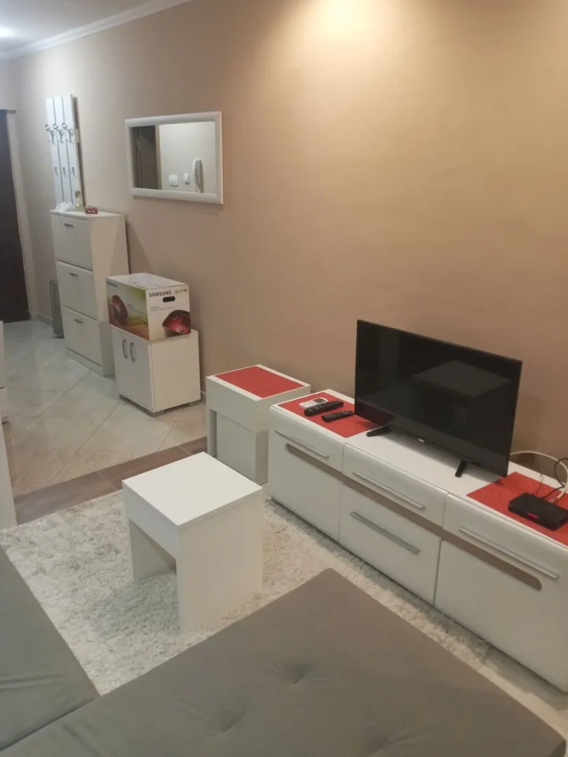 Dnevna soba sa TV komodom i hodnikom u pozadini.