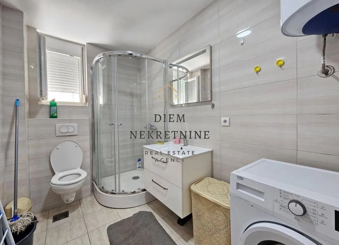 Compact bathroom with a shower cabin and a washing machine.