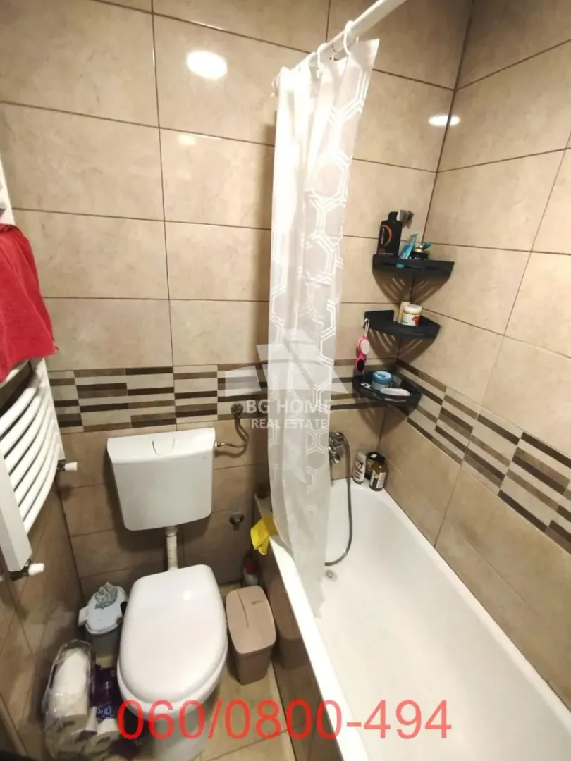 Manje kupatilo opremljeno kadom, wc šoljom i pločicama u bež tonovima.