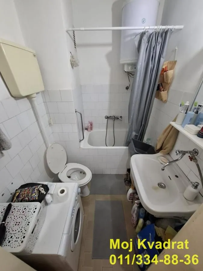 Smaller bathroom with a bathtub, toilet, washbasin, and washing machine.
